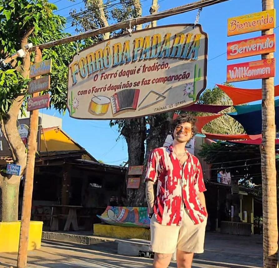 Lucas Tavano sorrindo em frente à entrada do Forró da Padaria